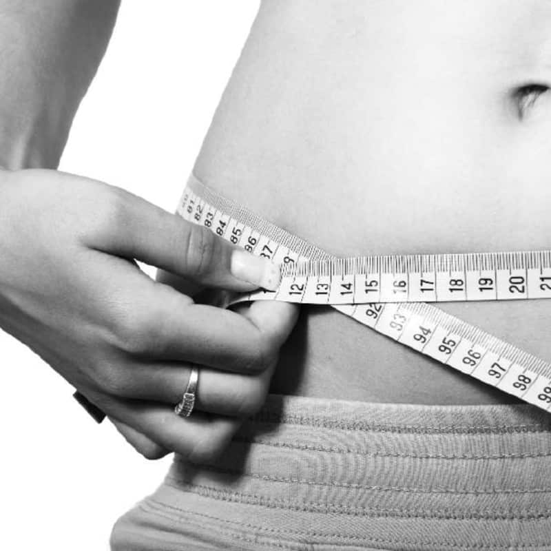 Weight loss results - Partial view of a women measuring her waist with a tape measure